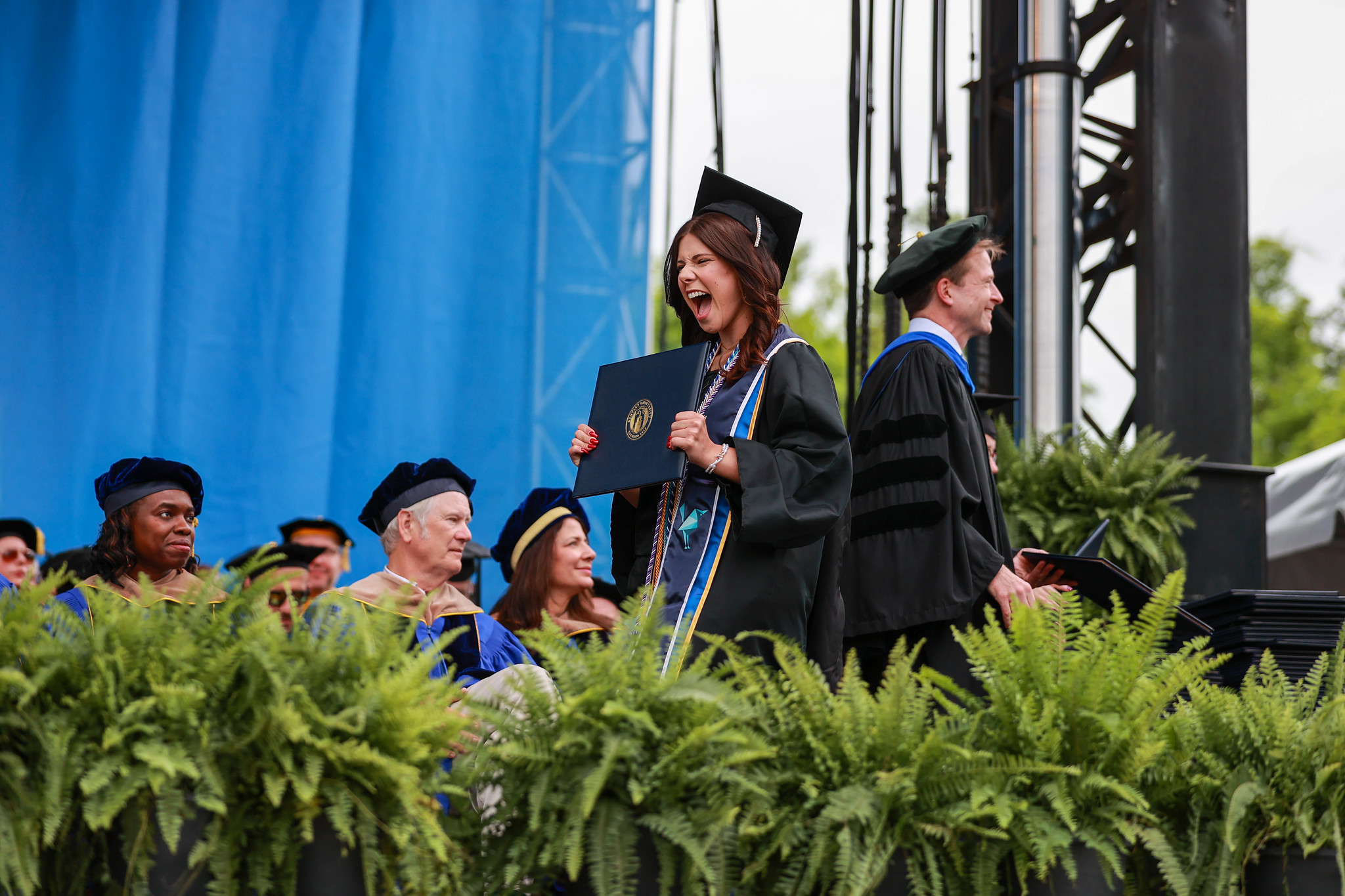 A graduate exclaims on stage after receiving her diploma