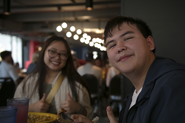 two students eating lunch together and smiling at camera