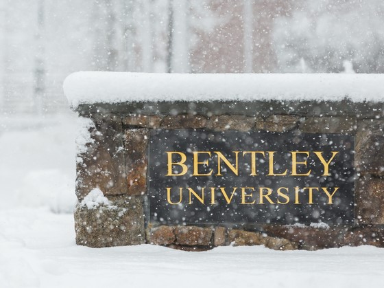 Photo of snow-covered stone wall with "Bentley University" welcome plaque. 
