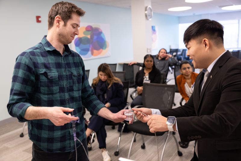 Bentley student Gilbert Li assists Boston Scientific employee Adam Nodiff in a demonstration of the company's LithoVue Elite, a medical device used to treat and manage kidney stones.