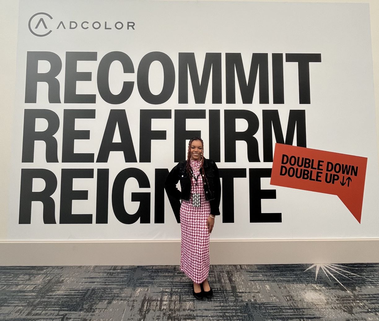 Bentley student Jaychele Nicole Schenck ’26 poses in front of a backdrop at the ADCOLOR 2023 conference