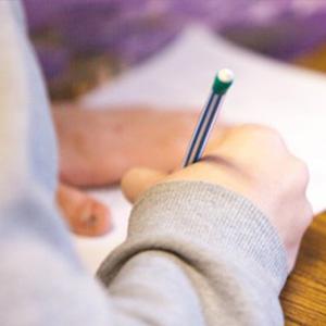 Photo showing person's hands holding a pencil over paper
