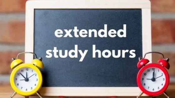 chalkboard with writing on it 'extended study hours' flanked by two alarm clocks