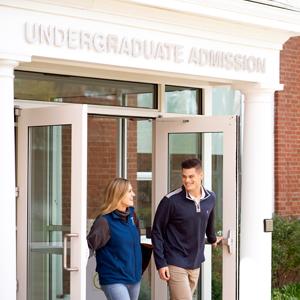 two students walk through admissions portico