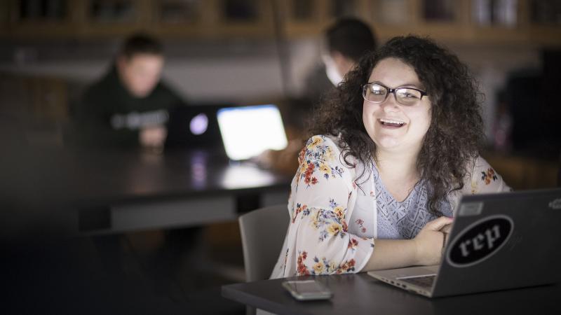 Student smiling in front of laptop
