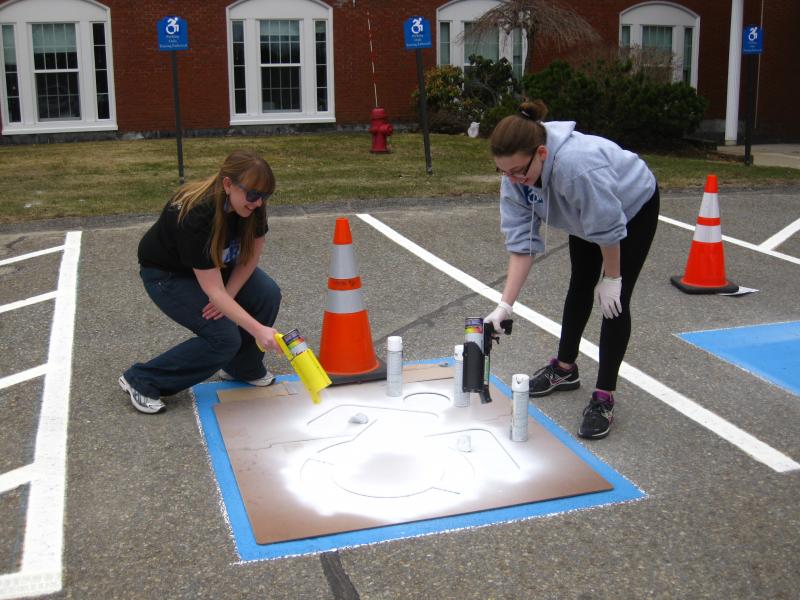 Students in parking lot adding handicap markers on parking spaces