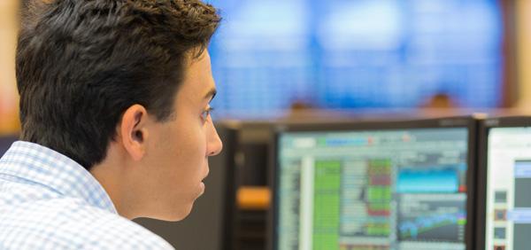 Student in trading room looking at a computer screen with bloomberg terminal