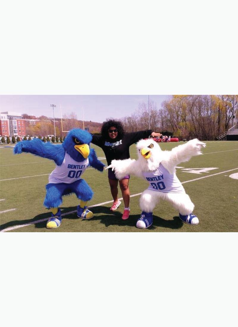 Two falcon mascots pose with a student