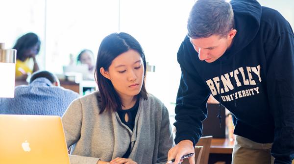 two students work together in the library at a table