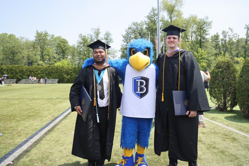 Two grads pose with Flex the Falcon