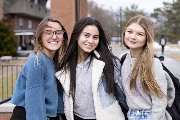 three students smile at the camera
