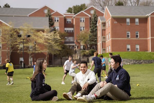 three students sit on the greenspace together at Bentley