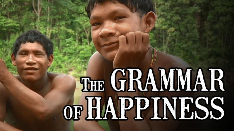 Closeup photo of two young male members of the Pirahã community, with "The Grammar of Happiness" superimposed over the photo in white text.